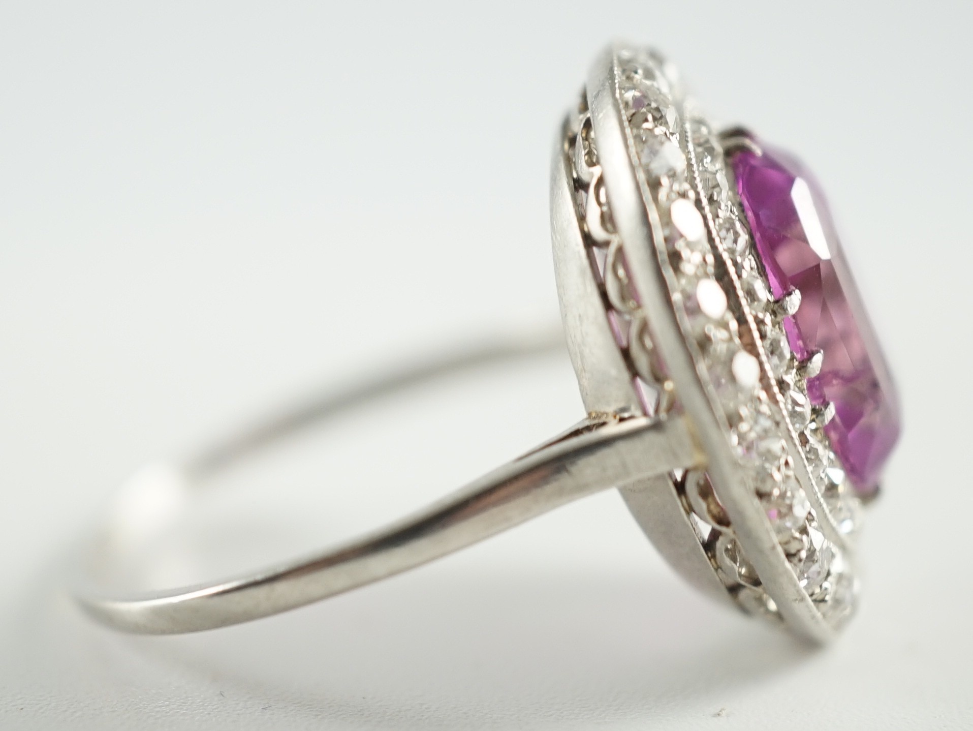 An early 20th century platinum, oval cut purple-pink sapphire and round cut diamond cluster set dress ring